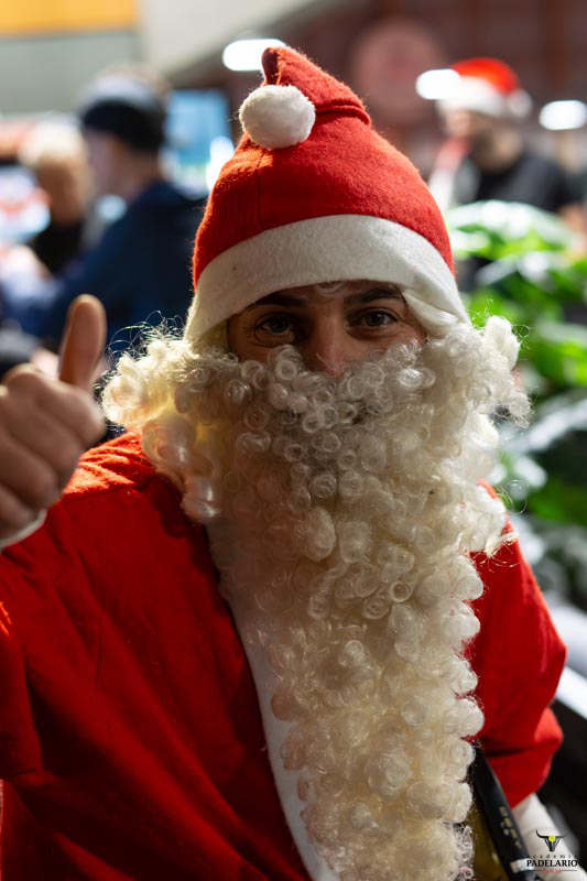 Mann im Weihnachtsmann-Kostüm gibt Daumen hoch vor verschwommenem Hintergrund.
