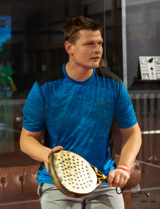 Ein Mann hält einen Schläger in einer Halle, konzentriert und aufmerksam.