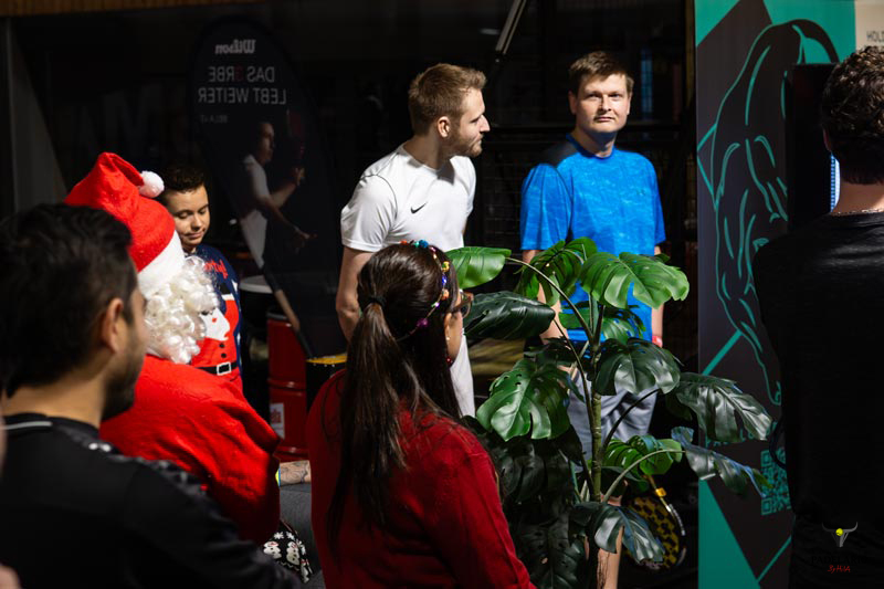 Menschen und Weihnachtsmann in einem Raum mit Text, Americano Turnier 19-12-25.