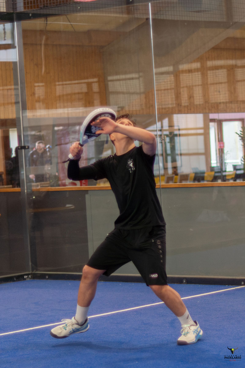 Männlicher Padelspieler schlägt Ball auf Indoor-Padelplatz beim Training.