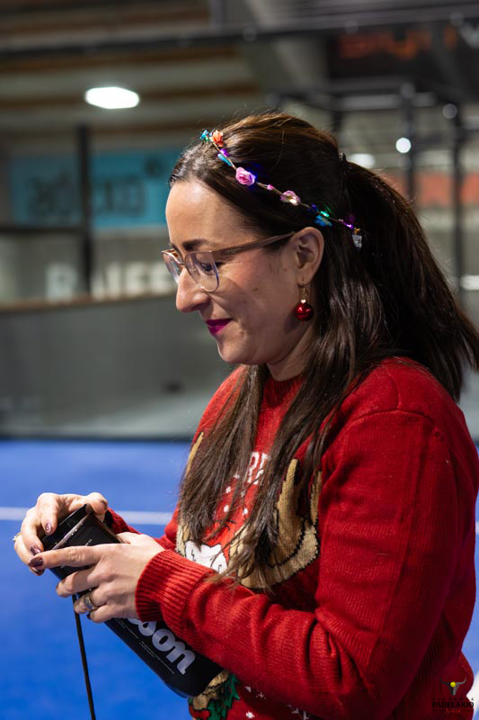 Frau mit Brille und rotem Pullover hält eine schwarze Flasche fest.