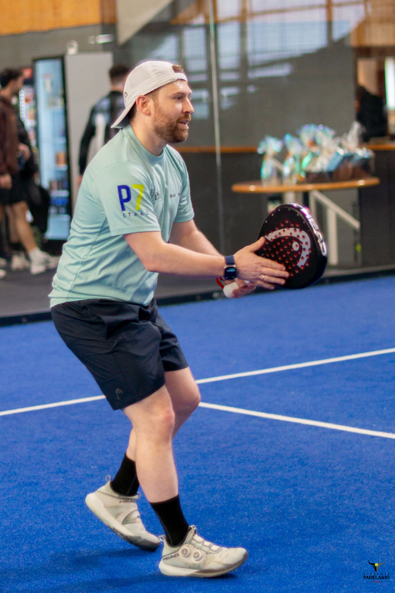 Mann auf blauem Padel-Court hält Schläger mit P-Logo.