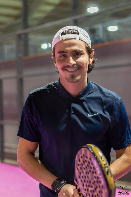 Ein Mann mit Schläger lächelt in die Kamera, Sportkontext