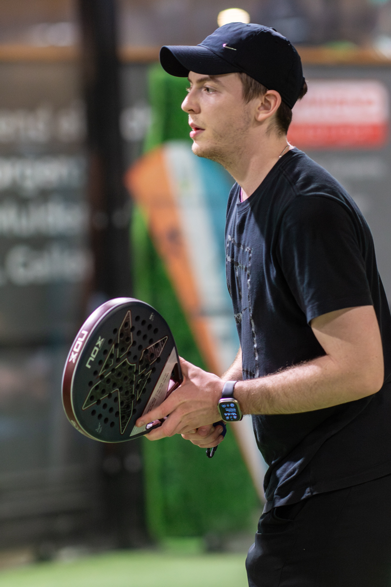 Mann mit Schläger hält vor dem Spiel. Text ist nicht lesbar