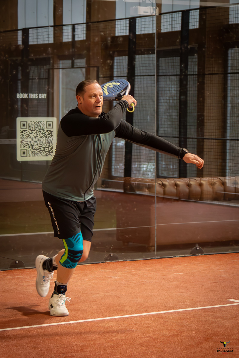 Spieler schlägt kraftvoll den Ball im Padel Match