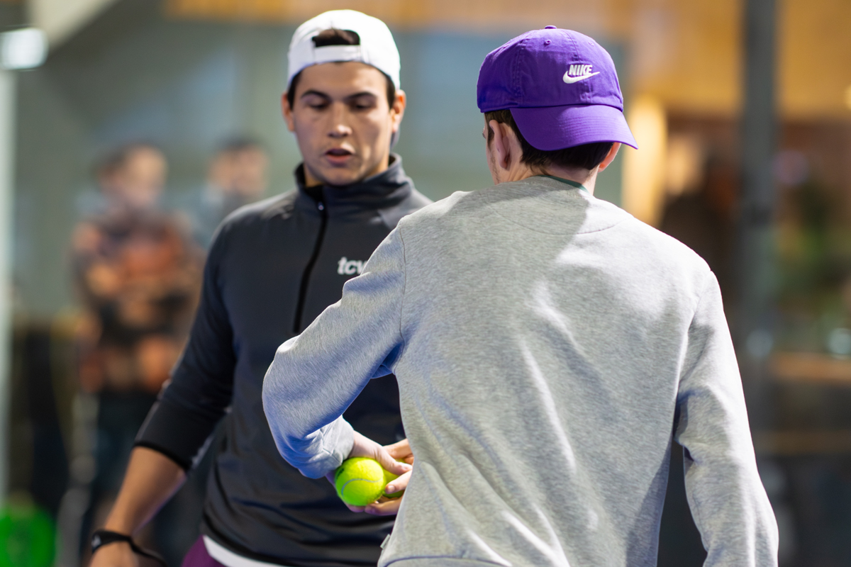 Zwei Männer halten einen Tennisball. Ein Mann trägt ein weißes Nike Cap.