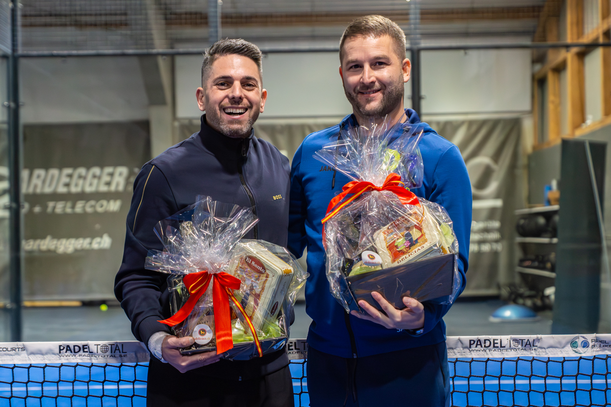 Two men smiling and holding gifts, background: Padel-Court, Bordegger Telecom, Turnier 30-11-25.