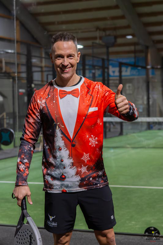 Mann im Weihnachtskostüm zeigt Daumen hoch und hält Schläger im Innenbereich.