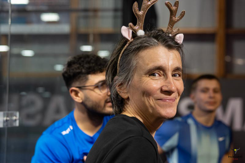 Frau mit Rentiergeweih lächelt fröhlich in die Kamera, Hintergrund unscharf.