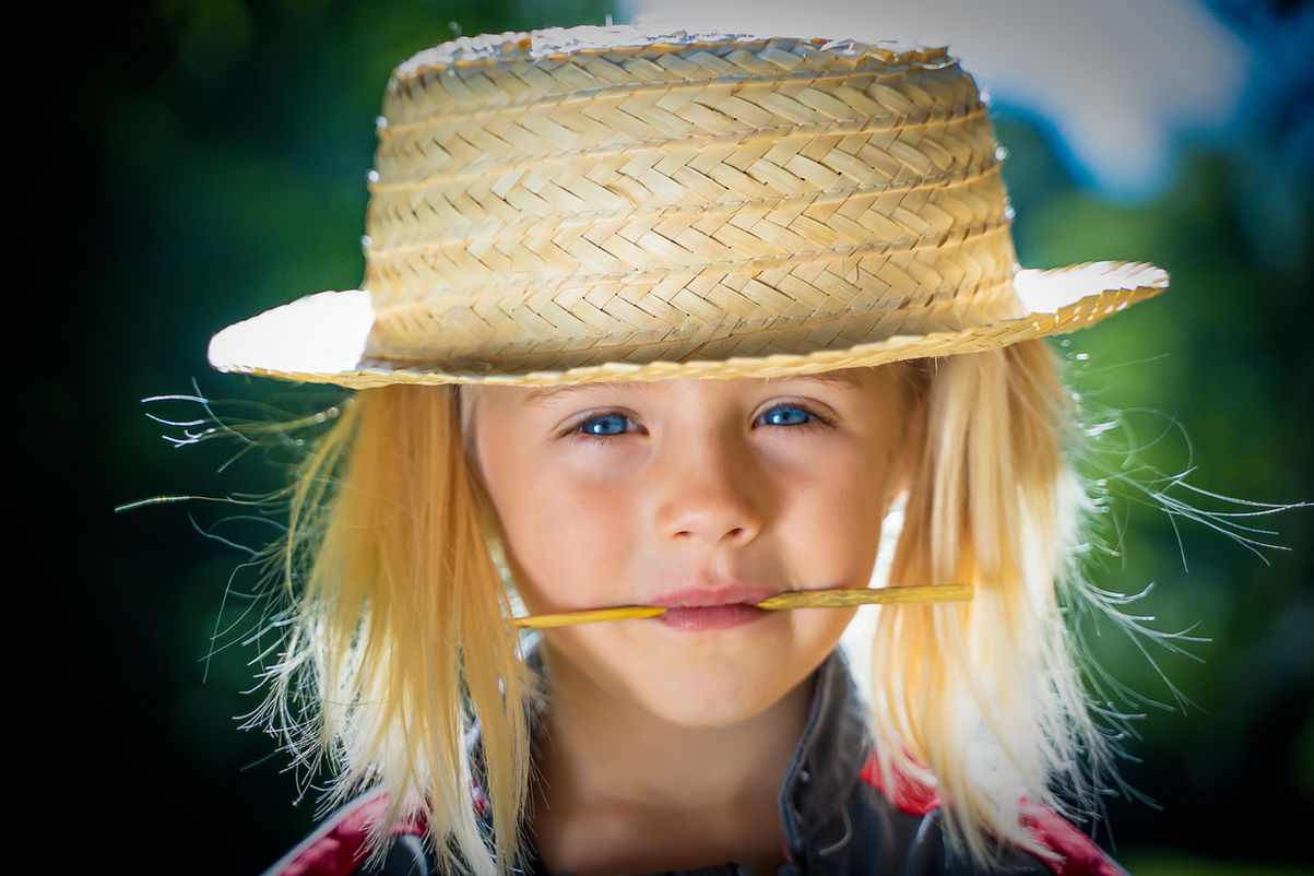 Jeune fille blonde porte chapeau de paille avec brin d'herbe photographe