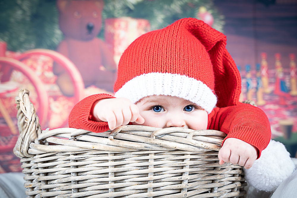 Bébé en costume de Père Noël joue dans un panier décoré. photographe