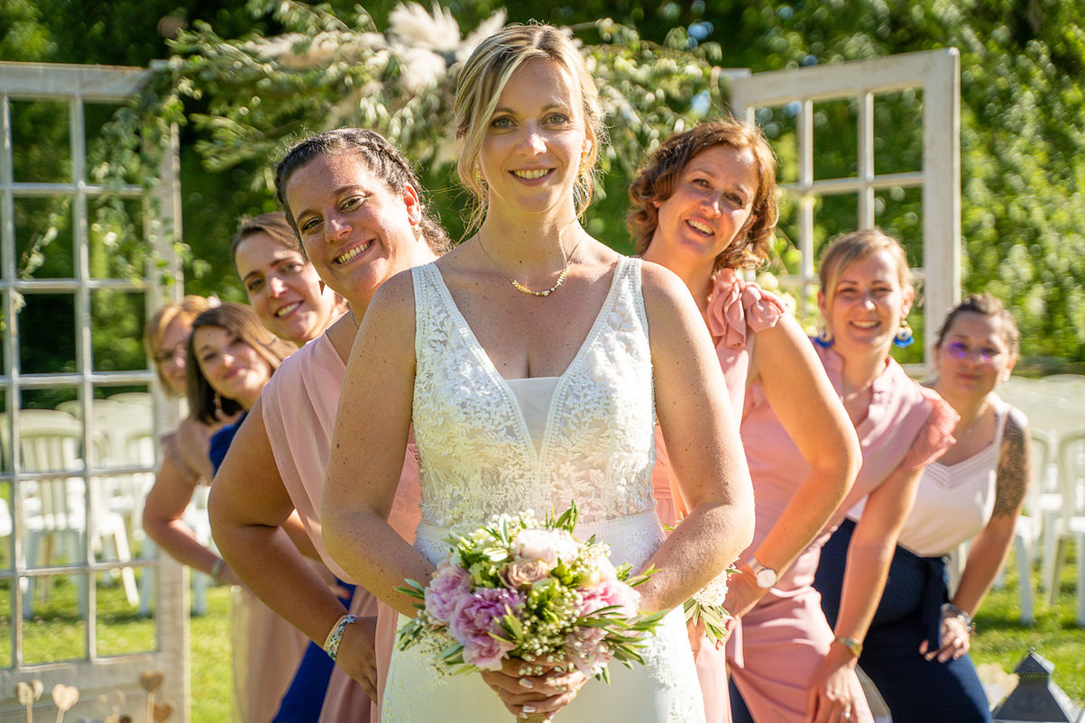 Bride in white dress smiles with bridesmaids, wedding day portrait, photographe
