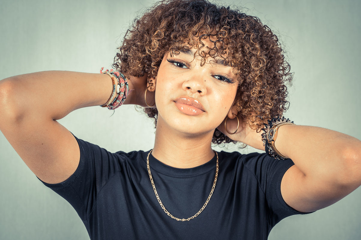 Portrait d'une jeune femme aux cheveux bouclés, regardant l'objectif, photographe.