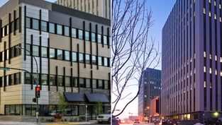 Two urban buildings at dusk. Left: modern with striped facade, red light. Right: tall with lit windows, bare branches in foreground.