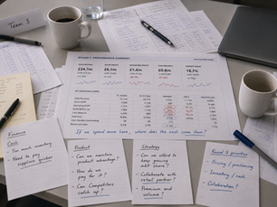 Business simulation performance reports, financial analysis and handwritten notes used by a team to review commercial decisions.
