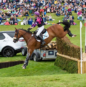 Ginny Howe riding a horse over a cross‑country fence