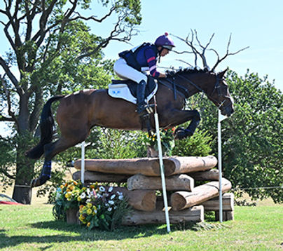 Ginny Howe riding a horse over cross-country jumps