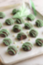A rimmed baking sheet with Mint Chocolate Protein Balls drizzled with mint chocolate.