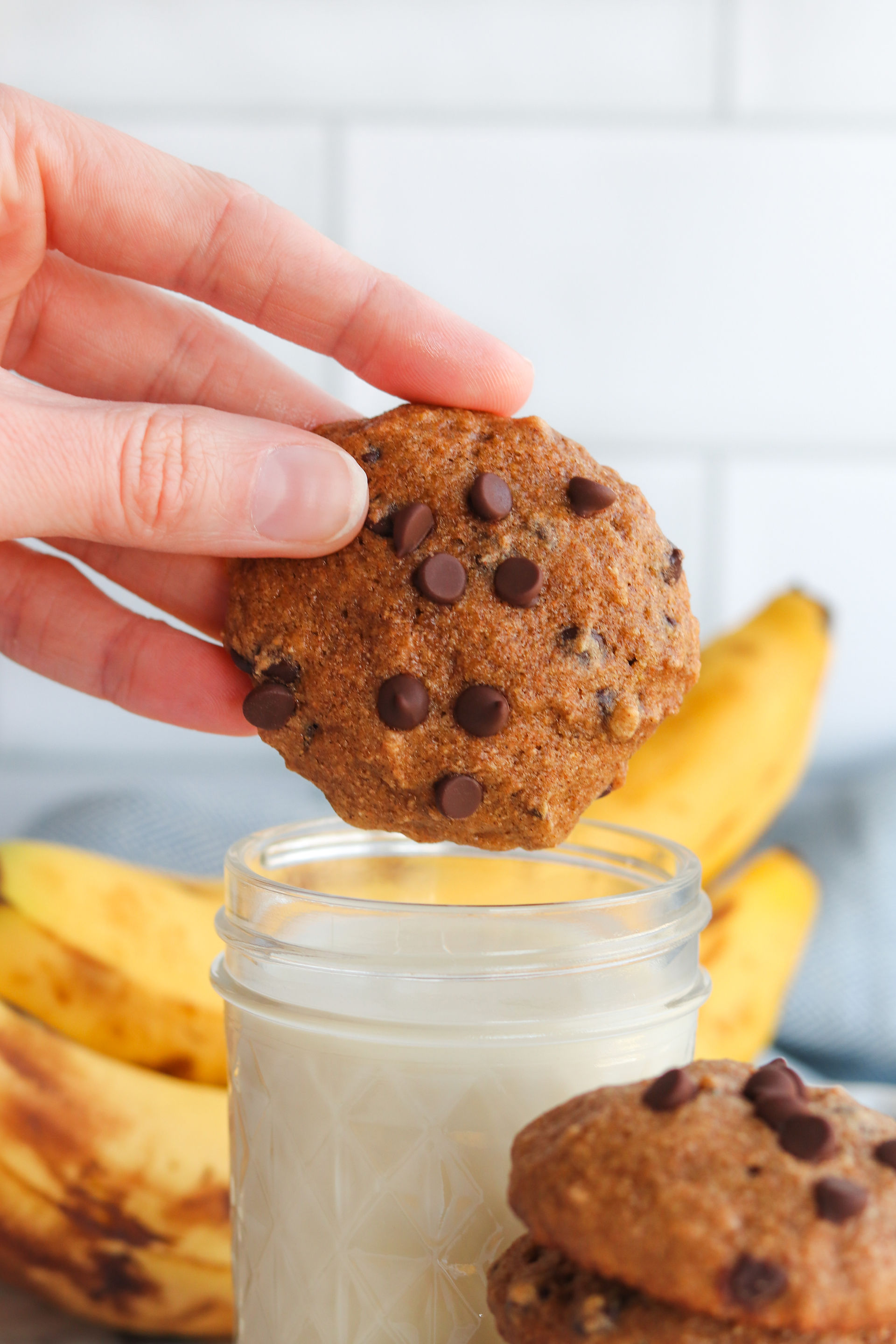 Chocolate Chip Banana Bread Cookie being dunked into a glass of milk.