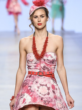 Giovane modella in un abito rosa con dettagli unici, sfila con eleganza alla Fashion Week, esprimendo la femminilità e il glamour della collezione.