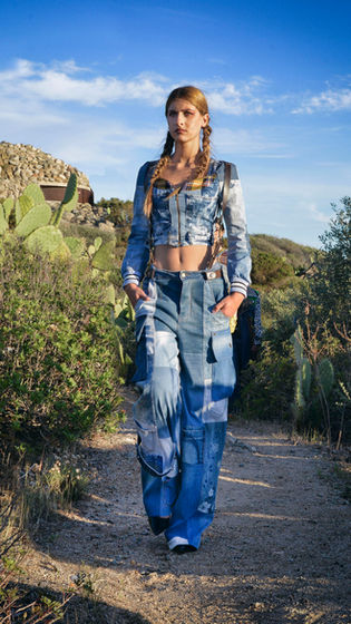 Modella in completo denim, sfila in un paesaggio verde.