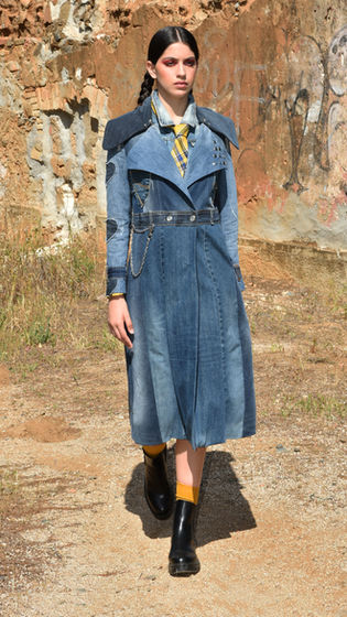 Modella in trench denim elegante, sfila con stile in mezza la natura.