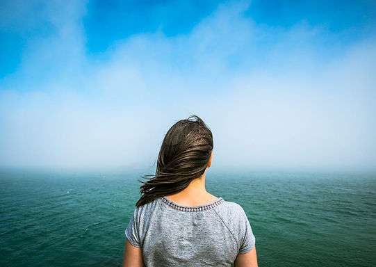 Woman glaring at the ocean reflecting.