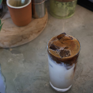 Iced horchata chai latte on concrete coffee bar with plants surrounding.