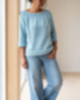 LEELOO Pullover in Hellblau, locker stehend zur weiten Jeans vor hellem skandinavischem Hintergrund