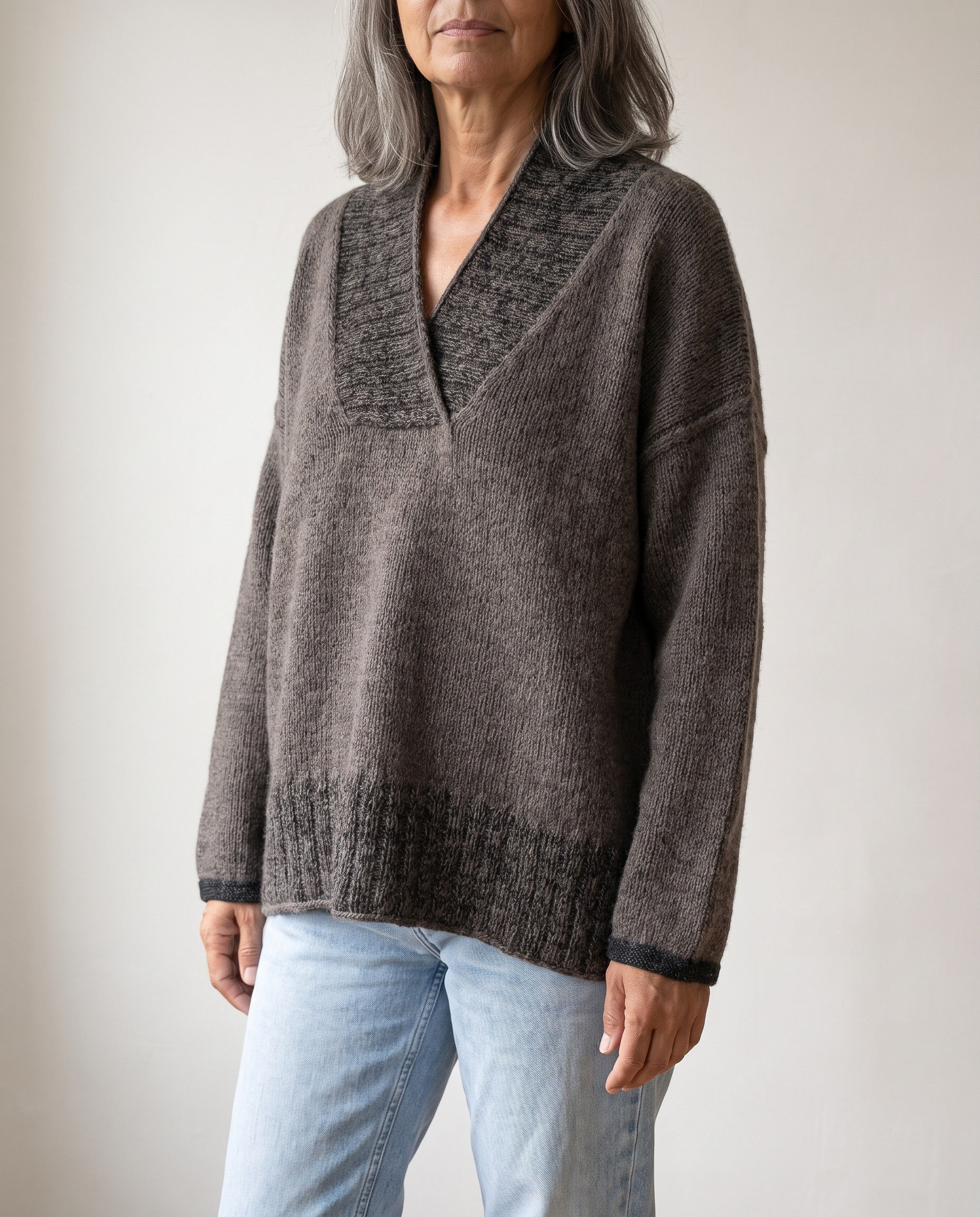 Modell trägt den graubraunen ASHLINE Sweater mit breitem Schalkragen und lockerem Oversize-Schnitt im hellen Studio.