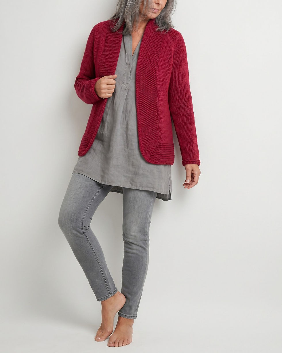 Rote ALVA Strickjacke von SAFRI DESIGN, getragen über grauer Leinenbluse und grauer Jeans, mit Schalkragen, Raglanärmeln und