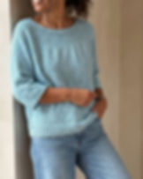 Hellblauer LEELOO Pullover mit Rundpasse, locker zur Jeans getragen vor heller Wand