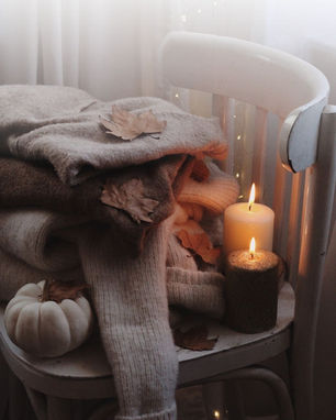 Stuhl mit gestrickten Pullovern und Kerzen