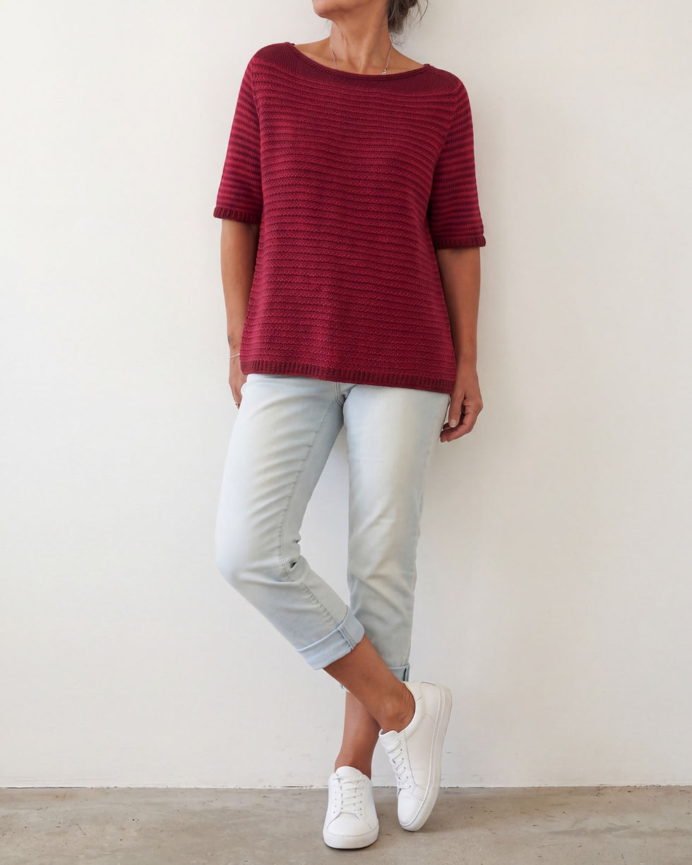 MALVA Shirt in Bordeaux und Rubin, locker fallend zu heller Jeans und weißen Sneakern getragen.
