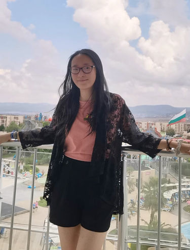 Evie on a balcony wearing pink and black 