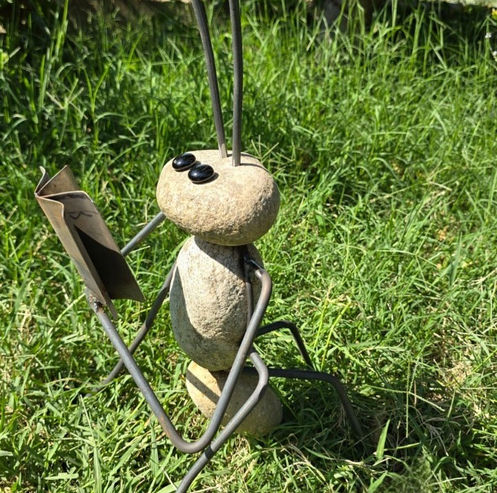 Escultura de hormiga leyendo un libro, realizada en hierro y piedra