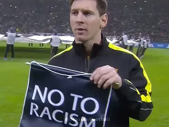 Messi segura cartaz NO TO RACISM e RESPECT em estádio lotado, em clima de apoio contra o racismo.