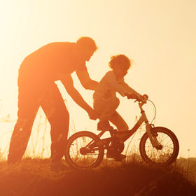 Silhouette of father teaching little dau