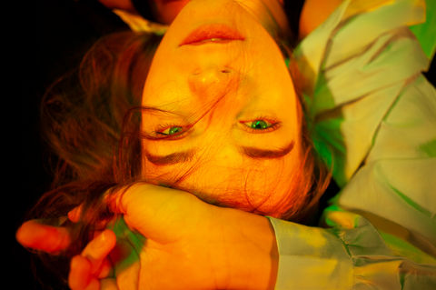 green eyed girl portrait, girl lies on black floor with her hand on her forehead looking into to camera. Omid Taslimi Photography