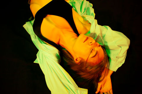 Girl lies on a black floor stretching her arm. Omid Taslimi Photography