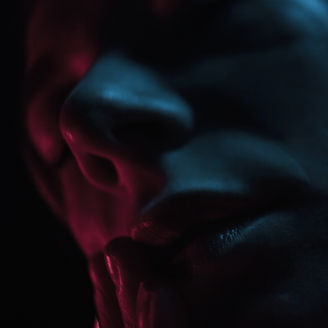 Super close of lips and nose of a girl in blue and red light, low key, dark photography studio Omid Taslimi Photography