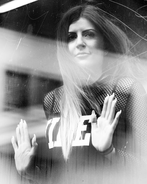 young woman standing behind a window und looking outside, black and white photography by Omid Taslimi, portrait