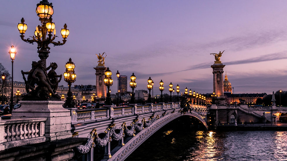 A beautiful bridge over the River Seine in Paris. The sky is purple at sunset and the lights of the bridge have just turned on.