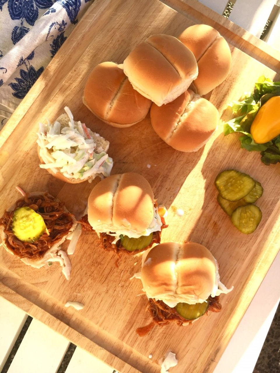 A board containing Instant Pot BBQ chicken sliders and toppings.