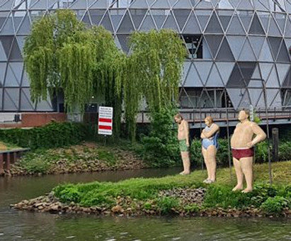 3 Duscher aus Beton. Alltagsmenschen in Badeanzug und Badehose als öffentliche Kunst. Betonmenschen