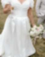 Close-up of the hands of a bride or tailor adjusting the fabric of a white dress skirt, highlighting the way the material dra