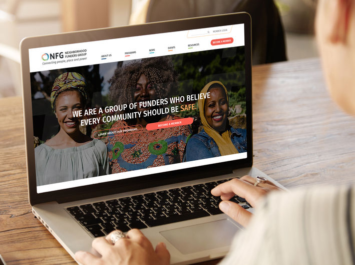 Image of a person looking at the opening page of a website which reads "We are a group of funders who believe every community should be safe."