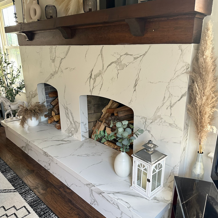 quartz stone fireplace with dark wooden mantel and decorative seasonal accents.