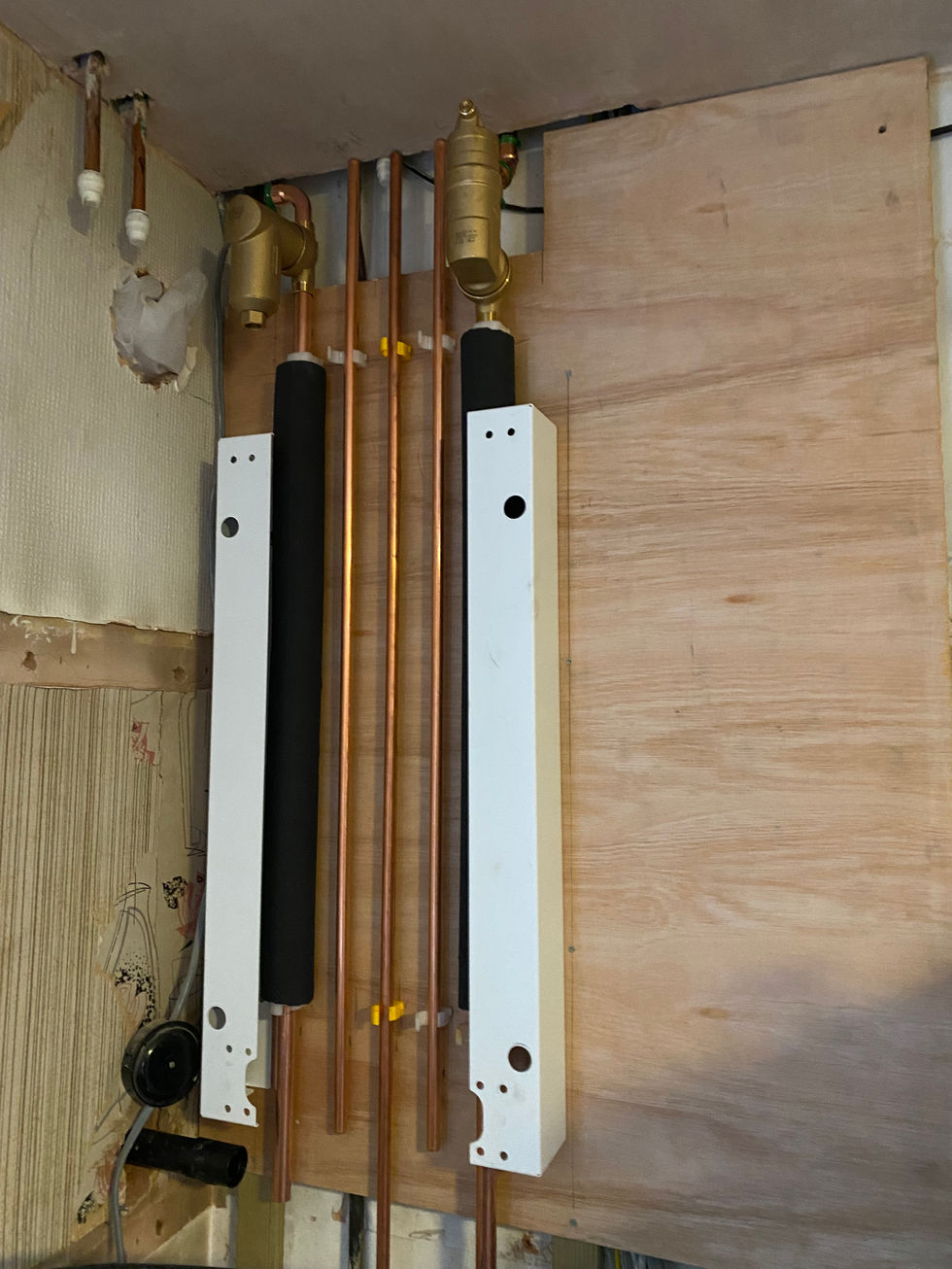 copper pipes are lined up on a wooden wall