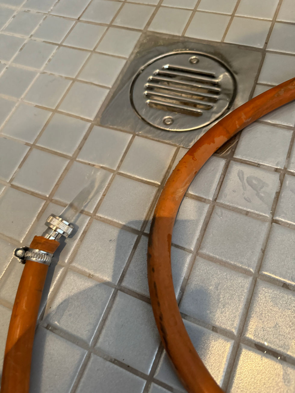 a hose is laying on a tiled floor next to a drain
